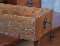 Drawer construction detail, early machine dovetail joinery. Not a typical machine made drawer joint used by all of the major Arts and Crafts furniture manufacturers after the very early period when hand dovetail joinery was performed. The circular drawer joint is known as a Knapp joint or commonly the half moon, pin and scallop or scallop and dowel.   Charles B. Knapp of Waterloo, Wisconsin patented his first machine in 1867, a later version revolutionized furniture drawer construction.  It is generally considered that it was no longer used after 1900 when machinery was developed that produced joinery that resembled the preferred hand dovetailed joint. Note the uncommon use of the more expensive fine quarter sawed white oak in the sides of the drawers.